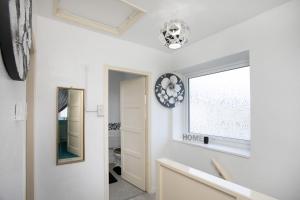 einen Flur mit weißen Wänden, einem Fenster und einem Spiegel in der Unterkunft Tsalach Short Lets in Nottingham + 33 Fotos