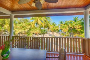 a table and chairs on a porch with a view of the beach at Wild Orchid in Placencia