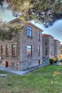 a large stone building with windows on a grass field at Amfipolis Root House in Próti