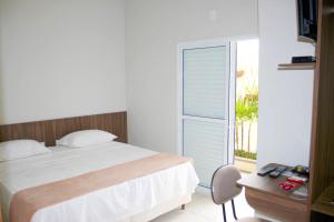 a bedroom with a bed and a large window at Hotel Redentor in Santa Vitória