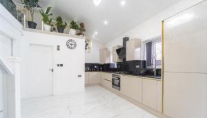 a kitchen with white cabinets and a clock on the wall at New Modern Stylish Villa Near City Centre Birmingham, with outdoor Hot Tub in Birmingham