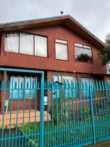 une maison rouge avec une clôture bleue devant elle dans l'établissement Casa Vintage Puerto Varas, à Puerto Varas