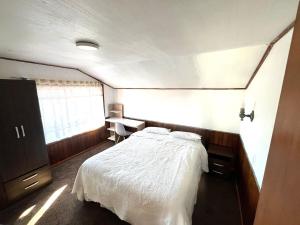 une chambre avec un lit blanc et un bureau dans l'établissement Casa Vintage Puerto Varas, à Puerto Varas