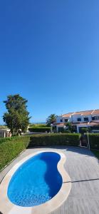 a swimming pool in front of a house with the ocean at Beach House Altura in Altura