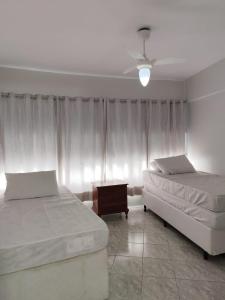 a bedroom with two beds and a window with curtains at 11A - Apto c/2 QUARTOS, Sala e Cozinha completa,1WC, 1 Vaga, Roupa de Cama e VIVO FIBRA in Guarujá