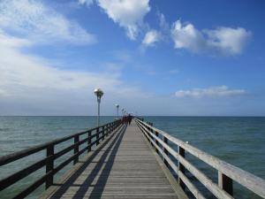 a wooden pier leading to the ocean with people on it at Apartment Fledermäuschen in Graal-Müritz