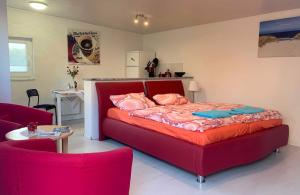 ein Schlafzimmer mit einem roten Bett und ein Wohnzimmer in der Unterkunft Bungalow mit Terrasse in Graal-Müritz