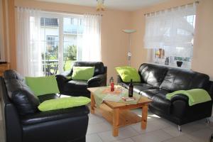 a living room with black leather furniture and green pillows at Ferienhaus Seeblick bei Dranske in Lancken