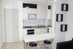 Una cocina con gabinetes blancos y una encimera con taburetes. en Thermas do Bosque, en Jeriquara