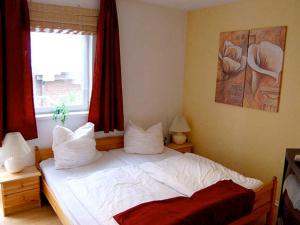 a bedroom with a bed with white sheets and a window at Ferienwohnungen Haus Mecklenburg in Elmenhorst