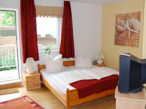 a bedroom with a bed and a tv and a window at Ferienwohnungen Haus Mecklenburg in Elmenhorst