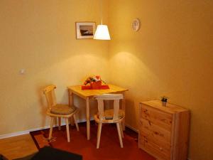 a dining room table with two chairs and a dresser at Ferienwohnungen Haus Mecklenburg in Elmenhorst +5 photos