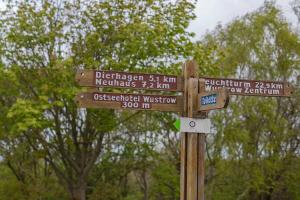 ein Holzschild mit Straßenschildern an einer Stange in der Unterkunft Doppelhaushälfte Wustrow in Wustrow