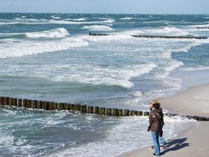 a woman walking on the beach looking at the ocean at Ferienhaus Loissin in Loissin
