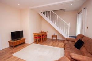 un soggiorno con un divano, una TV e un tavolo di 3 Bed Cottage Flat with Parking a Glasgow