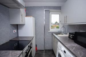 una cucina con un lavello e un frigorifero bianco di 3 Bed Cottage Flat with Parking a Glasgow Altre 8 foto