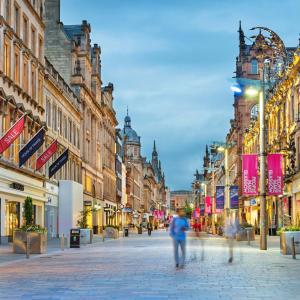 una strada di città con gente che cammina per strada di 3 Bed Cottage Flat with Parking a Glasgow
