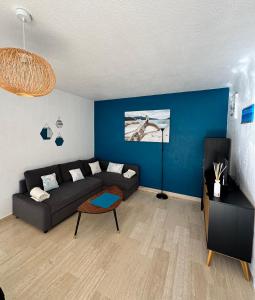 a living room with a black couch and a blue wall at T2 appartement Golfe Juan 47m2 plages et port in Vallauris