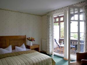 a bedroom with a bed and a sliding glass door at Hotel Hiddensee Hitthim in Kloster +2 photos