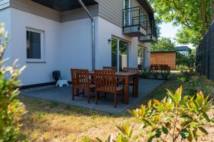 eine Terrasse mit einem Holztisch und Stühlen in der Unterkunft Ferienwohnungen am Darßer Ort inkl Wäschepaket in Wieck