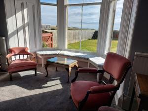 a living room with two chairs and a table and a window at Lower Rocklands in Earlsferry