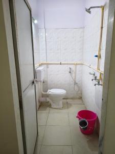 a bathroom with a toilet and a pink bucket at Hotel Vijay Palace Lodging Boarding in Bhiwandi +19 photos