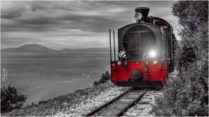 a red and black train on the tracks near the ocean at Alkifron Hotel in Kala Nera
