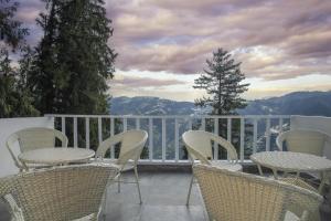 eine Gruppe von Stühlen und Tischen auf einem Balkon in der Unterkunft Echor Backwoods Villa Narkanda in Narkanda