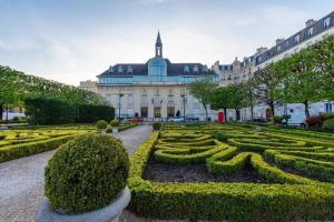 a large building with a garden in front of a building at Chez Sophie, cosy et calme, à deux pas de Paris in Saint-Mandé