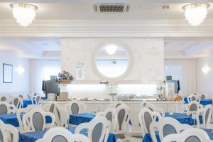 a banquet hall with blue and white chairs and a window at Hotel Croce di Malta e Mexico in Cesenatico
