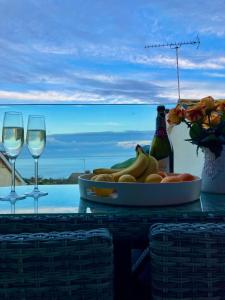 a table with a bowl of fruit and two glasses of wine at Kittiwake Retreat, a luxury escape by the sea! in Gorran Haven