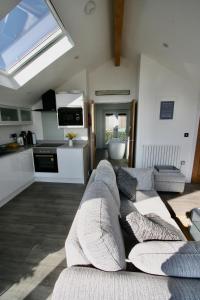 a living room with a couch and a kitchen at Kittiwake Retreat, a luxury escape by the sea! in Gorran Haven