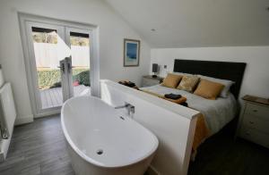 a bathroom with a tub and a bed and a bath tub at Kittiwake Retreat, a luxury escape by the sea! in Gorran Haven