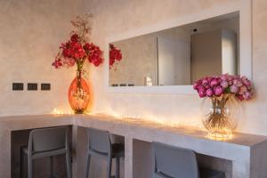 two vases with flowers on a counter with a mirror at Malvasiasuites in Bologna +43 photos