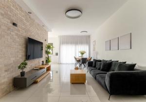 a living room with a black couch and a brick wall at פנטהאוז העצמאות in Qiryat Ata