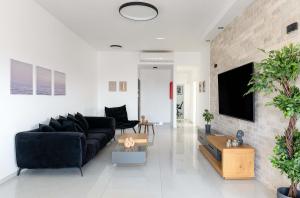 a living room with a black couch and a brick wall at פנטהאוז העצמאות in Qiryat Ata
