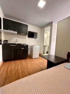 a room with a kitchen with a bed and a refrigerator at Loft e Suites Temporada in Balneário Camboriú