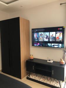 un salon avec une télévision et un meuble noir dans l'établissement Belrose Place, à Accra