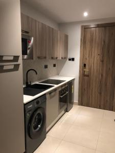 une cuisine avec une machine à laver et un évier dans l'établissement Belrose Place, à Accra