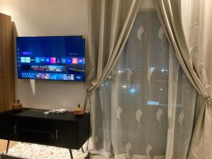 un salon avec une télévision et un rideau dans l'établissement Belrose Place, à Accra 2 autres photos