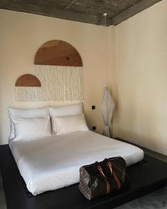 a white bed with a bag sitting on top of it at AMMA Boutique Hotel in Ahangama
