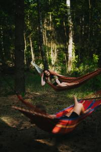 a woman laying in a hammock in a forest at Glamp Podróżnika i Marzyciela in Rogówko
