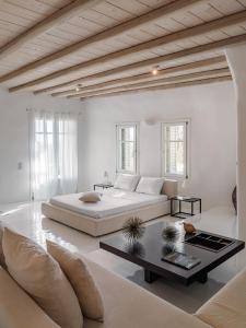 a white bedroom with a large bed and a table at Villa Zen Mykonos in Mýkonos City