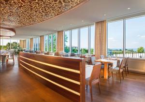 a restaurant with tables and chairs and large windows at Oberwaid - Das Hotel. in St. Gallen