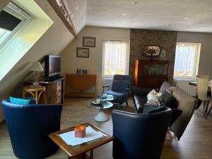 a living room with a couch and chairs and a tv at L Atypik à L ancienne forge in Muhlbach-sur-Munster