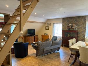 a living room with a staircase and a table and chairs at L Atypik à L ancienne forge in Muhlbach-sur-Munster