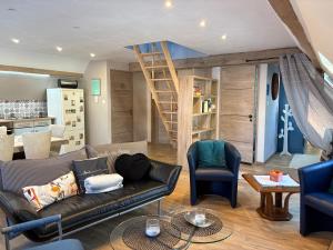 a living room with a couch and a staircase at L Atypik à L ancienne forge in Muhlbach-sur-Munster