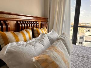 a bedroom with a bed with pillows and a window at Mimah's cozy getaway near JKIA at Taurus Residences in Nairobi