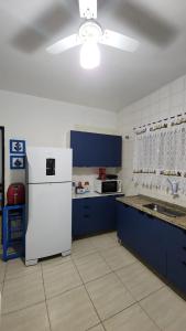 a kitchen with blue cabinets and a white refrigerator at Casa Jardim do Mar - Ubatuba - Praia Grande in Ubatuba