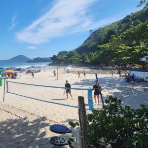 a group of people playing volleyball on a beach at Casa Jardim do Mar - Ubatuba - Praia Grande in Ubatuba +16 photos